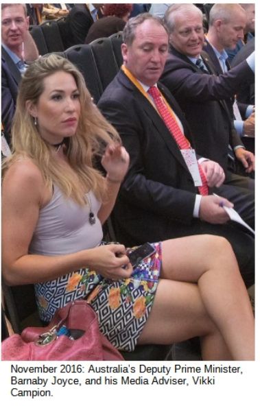 Photo caption - November 2016: Australia's Deputy Prime Minister, Barnaby Joyce, and his Media Adviser, Vikki Campion.

Photo taken at a public event, with people sitting on rows of seats. Joyce and other men are dressed in business attire - suits & ties.

Campion is wearing casual gear - a tight-fitting sleeveless top and an ultra-short shirt.

Joyce is looking down at Campion's crossed legs, while Campion twirls her hair.