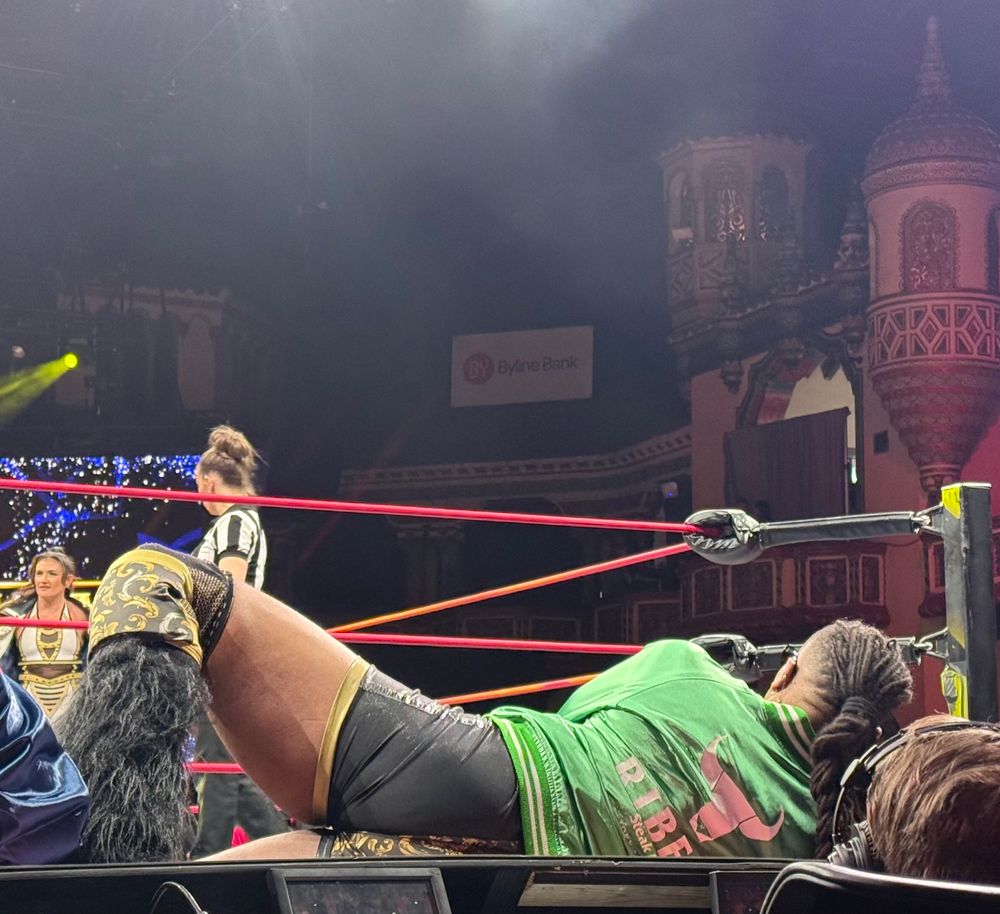 Mason Madden lies on his side on the announce table, with one leg bent so that his knee is up in the air.