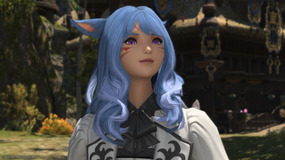 A screenshot from Final Fantasy 14. It's a close-up of my character Kahmeerya, a female Seeker Miqo'te with long blue hair and purple eyes. She is strolling in the streets of Old Gridania, a smile on her face. Her head is slightly to the right and slightly upwards. She is wearing a sort of refined light grey coat that has a black collar with ribbons. In the background we can see a bit of the scenery of Gridania with the Leatherworkers' Guild on the right side.