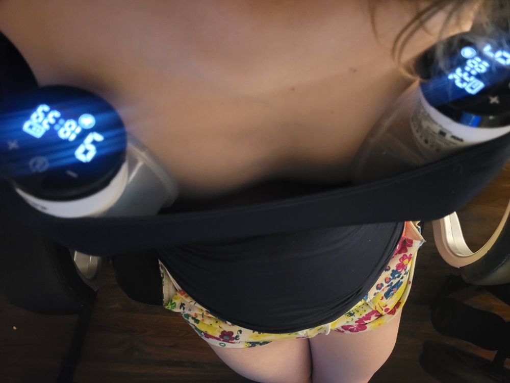 Cassidy down-blouse, 2 breast pumps tucked in a navy strappy cami top, floral shorty shorts.