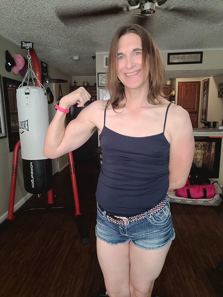Cassidy standing, lil flex, short jean shorts with black belt with pink and white jewels and a navy strappy cami top.
