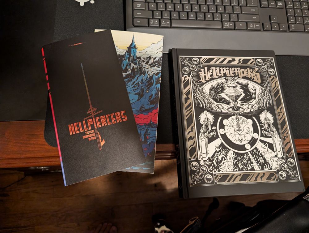 The beautiful HELLPIERCERS RPG and its map card foldouts on a cool guy's desk.