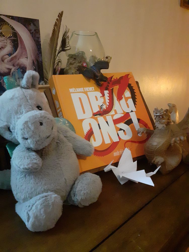 La couverture du livre Dragons! de Mélanie Fievet, entourée de peluches et goodies dragons.