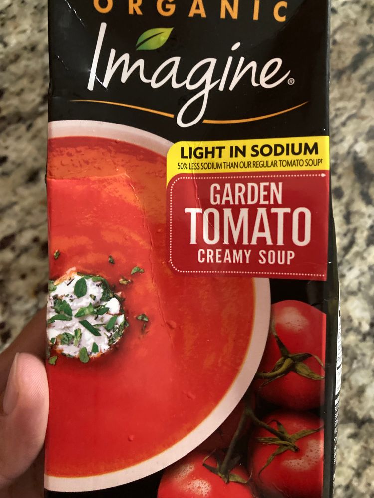 Photo of a tetrapak of garden tomato creamy soup by the brand imagine, being held by a human hand