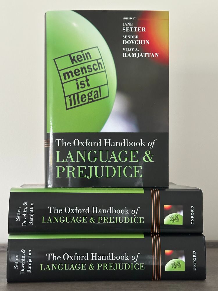 This is a photo showing a copy of the handbook standing on top of two others laid horizontally.