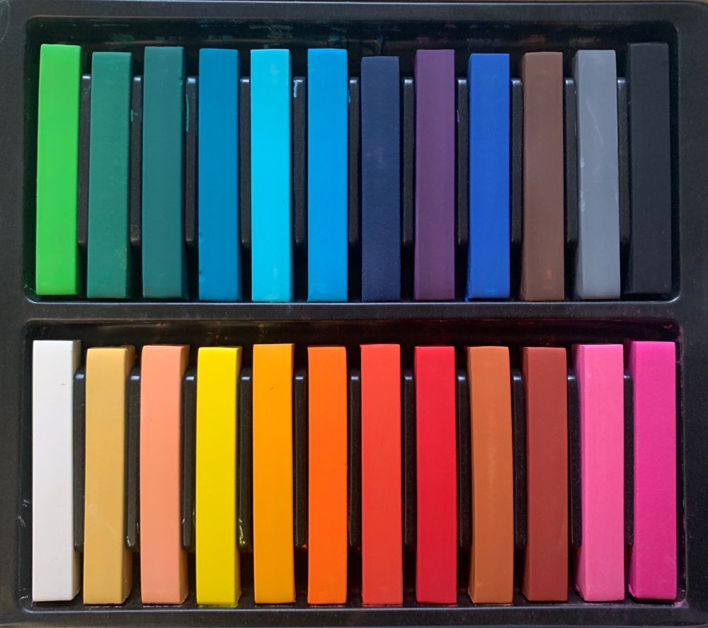Two rows of colourful chalk pastels in a black tray. 