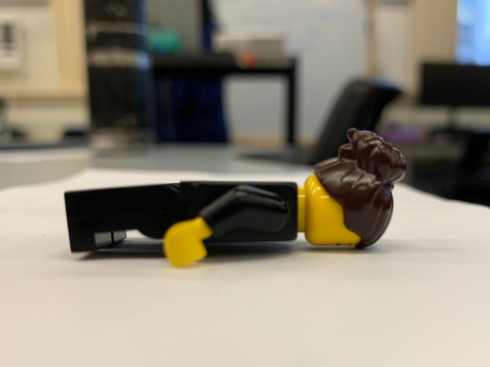 A LEGO minifigure lies face down on a table. 