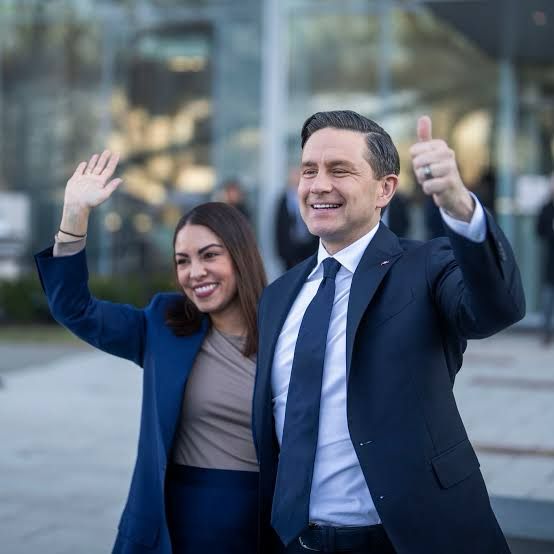 Pierre Poilievre in a suit gives a thumbs up. 
His political wife that we’re not supposed to talk about in political posts gives a high five to someone off screen. They’re the worst.