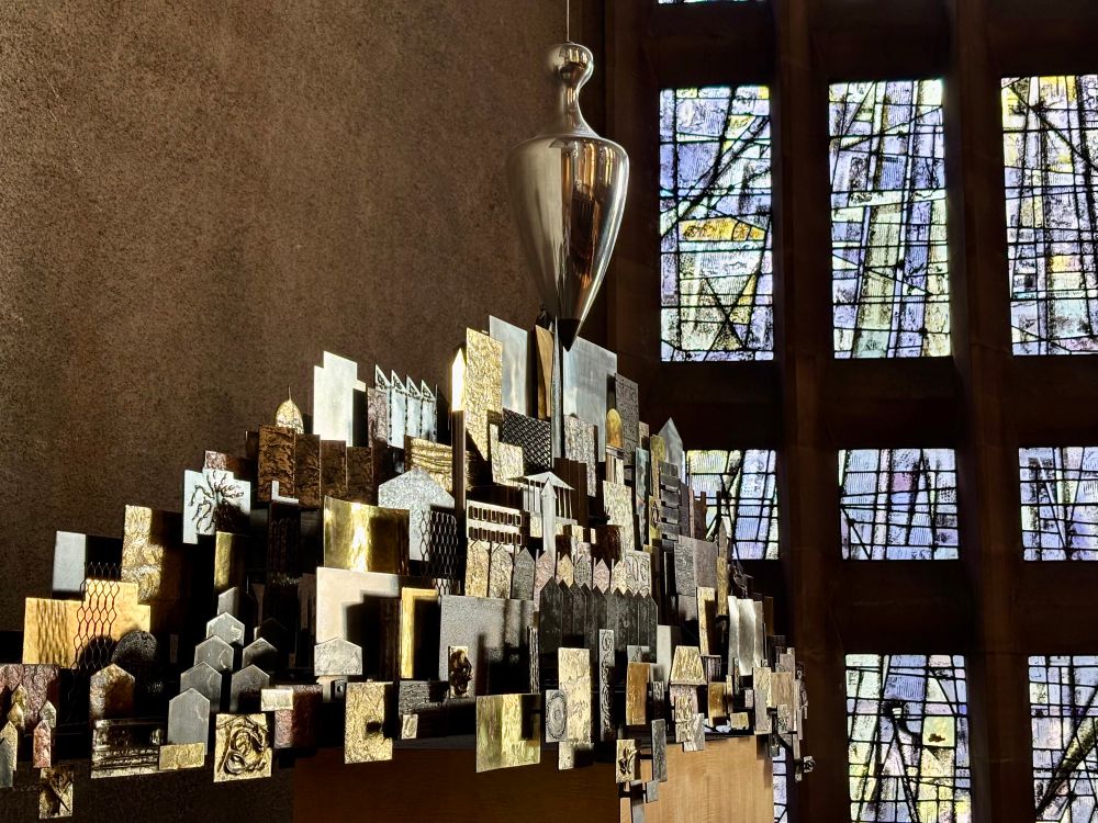 A metal sculpture in front of stained glass window.  