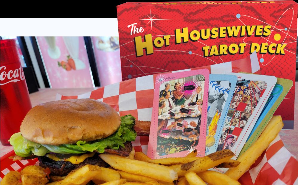 A basket with a cheeseburger and frys from Rosie's Diner in Aurora Colardo with colorful tarot cards in it, the box for the Hot Housewives Tarot looming behind.