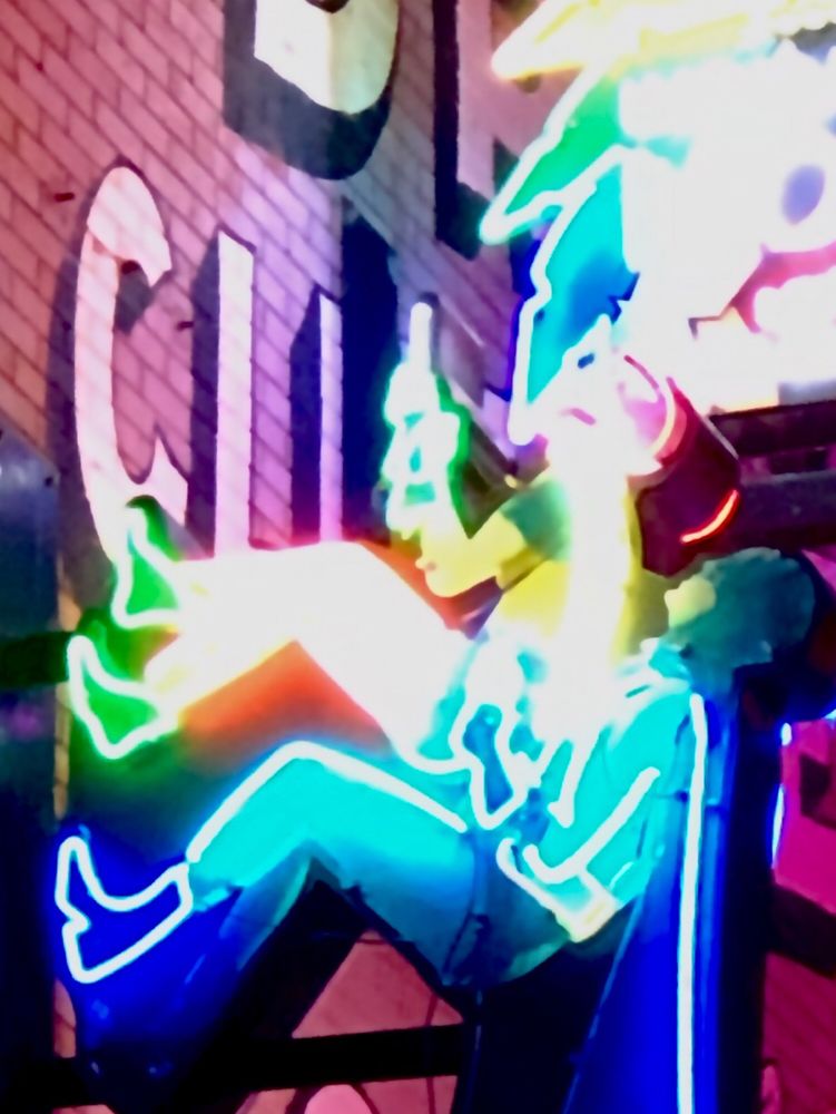 Batman and Robin neon light, made to look like they’re climbing up the side of the brick building. 