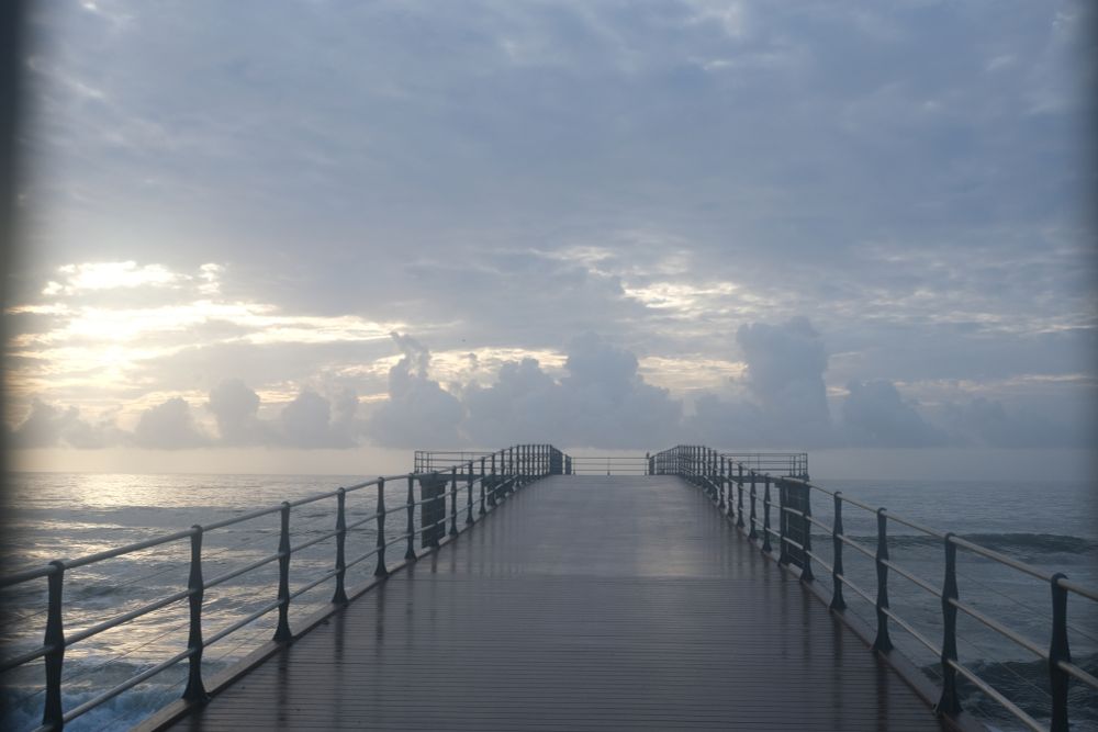 photo of clouds over an ocean pier that, for no reason, makes me think of the tacoma narrows bridge