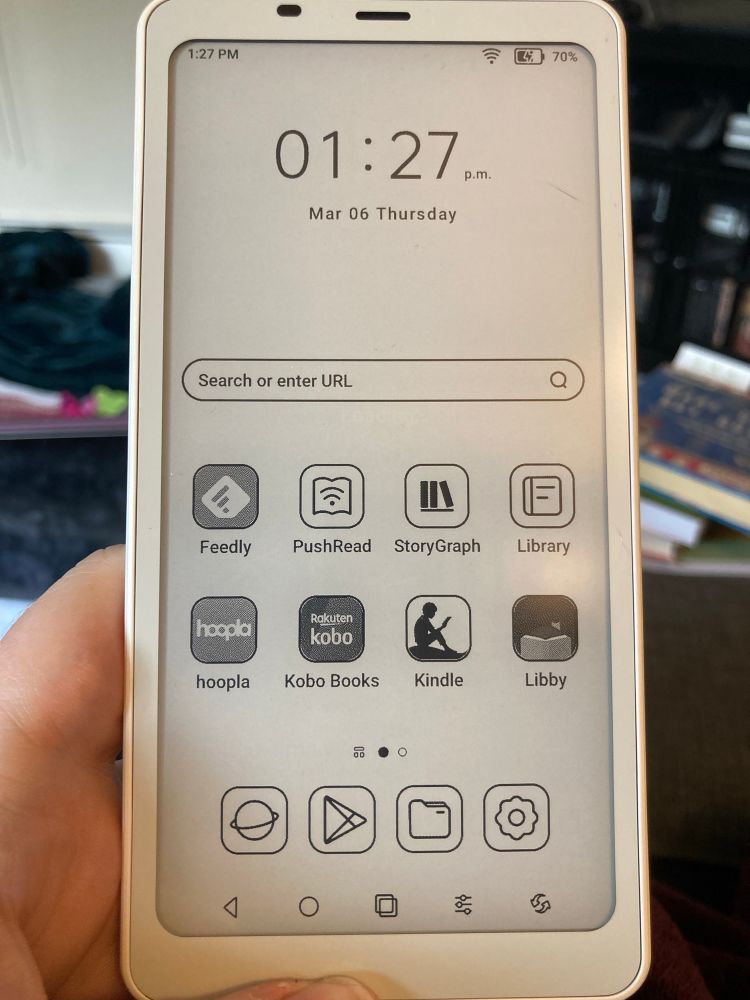 A photo of a hand holding a refurbished white Boox Palma ereader. 