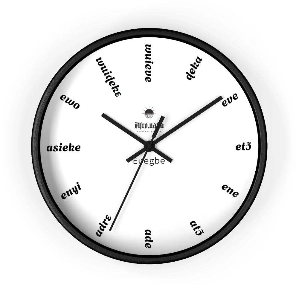 A white clock with a black base that has words in place of the usual cardinal numbers. These words are cardinal numbers in Éʋegbe.