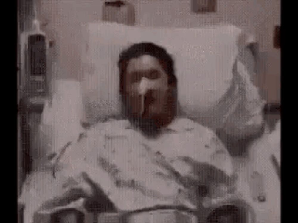 a man is laying in a hospital bed with an oxygen mask on .