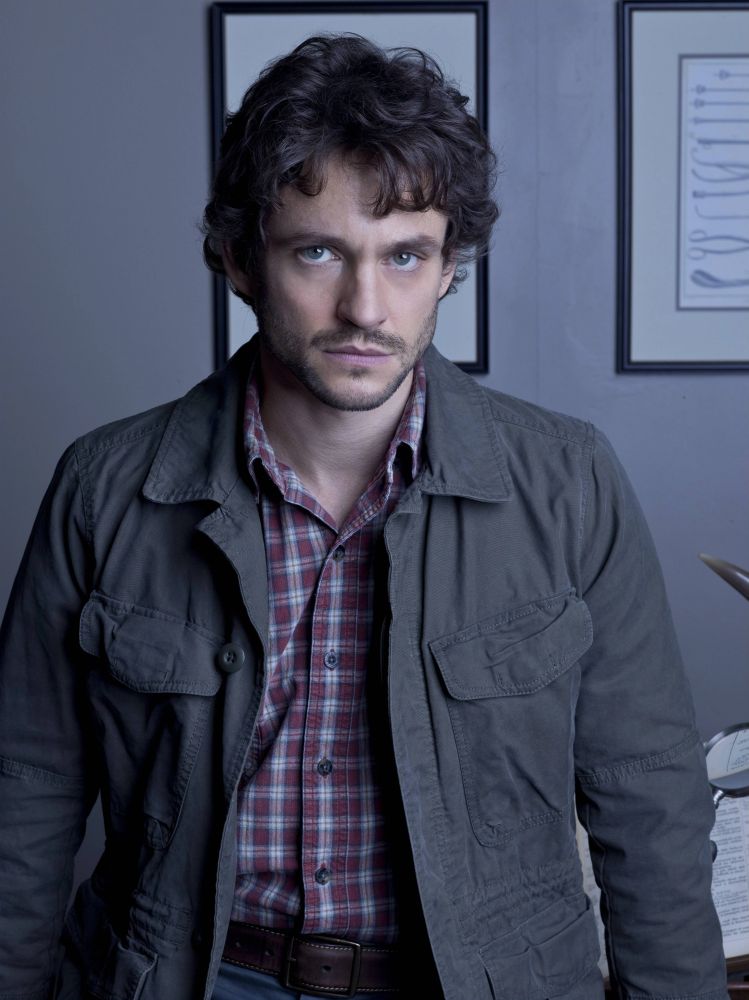 a man with scruffy beard and unkempt hair wearing a wrinkled coat and plaid shirt