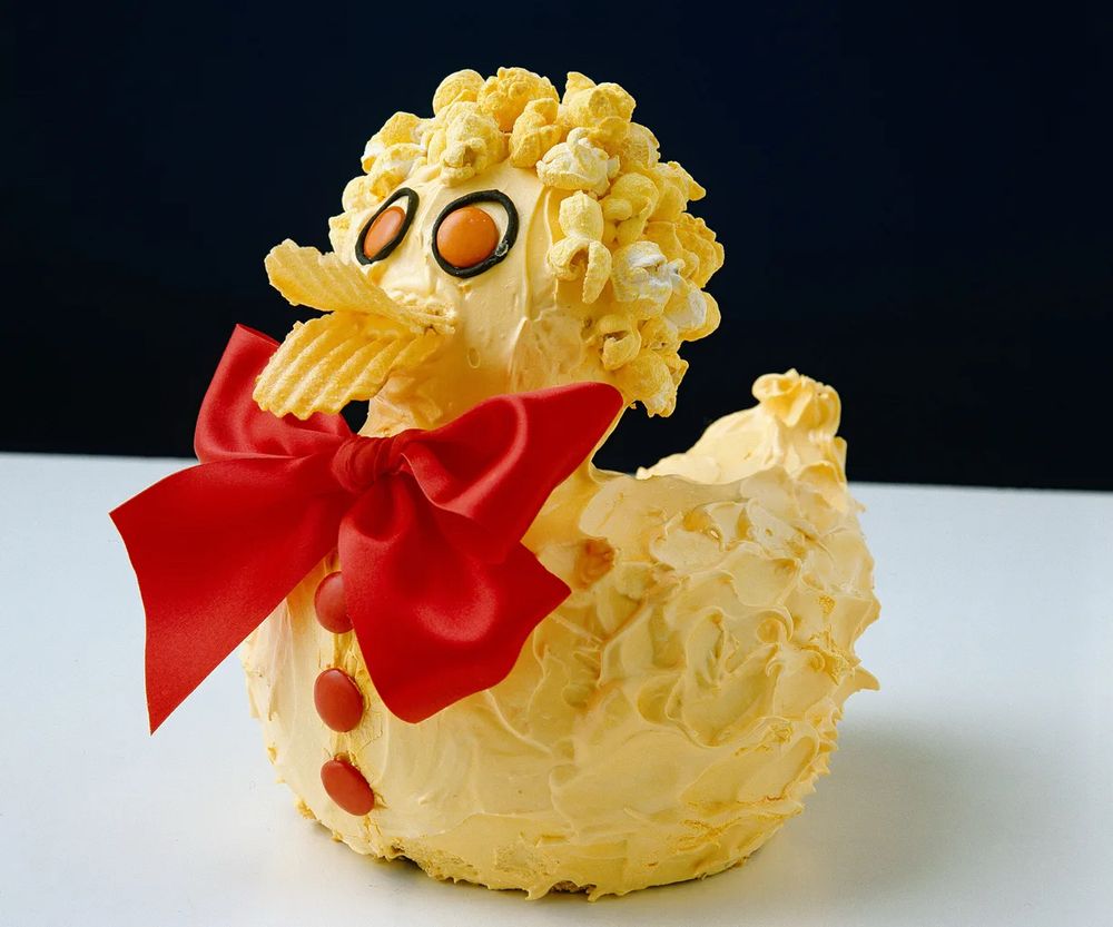 A duck-shaped cake, as featured in the Australian classic Women’s Weekly Birthday Cake cookbook. It is covered in yellow icing and features lolly accents for its eyes and buttons, popcorn for its ‘hair’, crinkle-cut chips for its duck bill and a BIG red bow tied around its neck. Notorious for its difficult assembly, it has been the bane of parents everywhere since the ‘80s; likely even more so since it featured in an episode of Bluey. At least now the millennial kids who picked it are getting their comeuppance as parents.