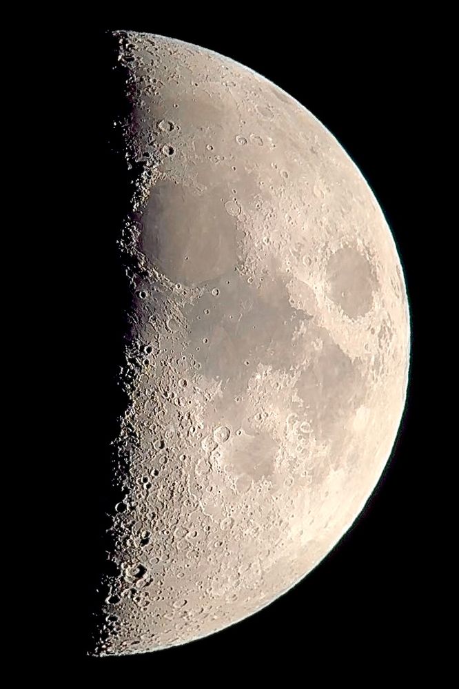 A very fat waxing crescent moon filling the frame, featuring craters and lunar lava flows, or maria 