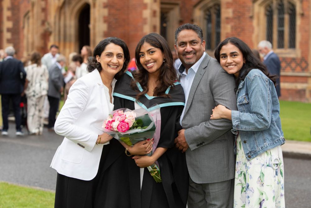 Image shows a female graduate holding a bunch of flowers with her family.