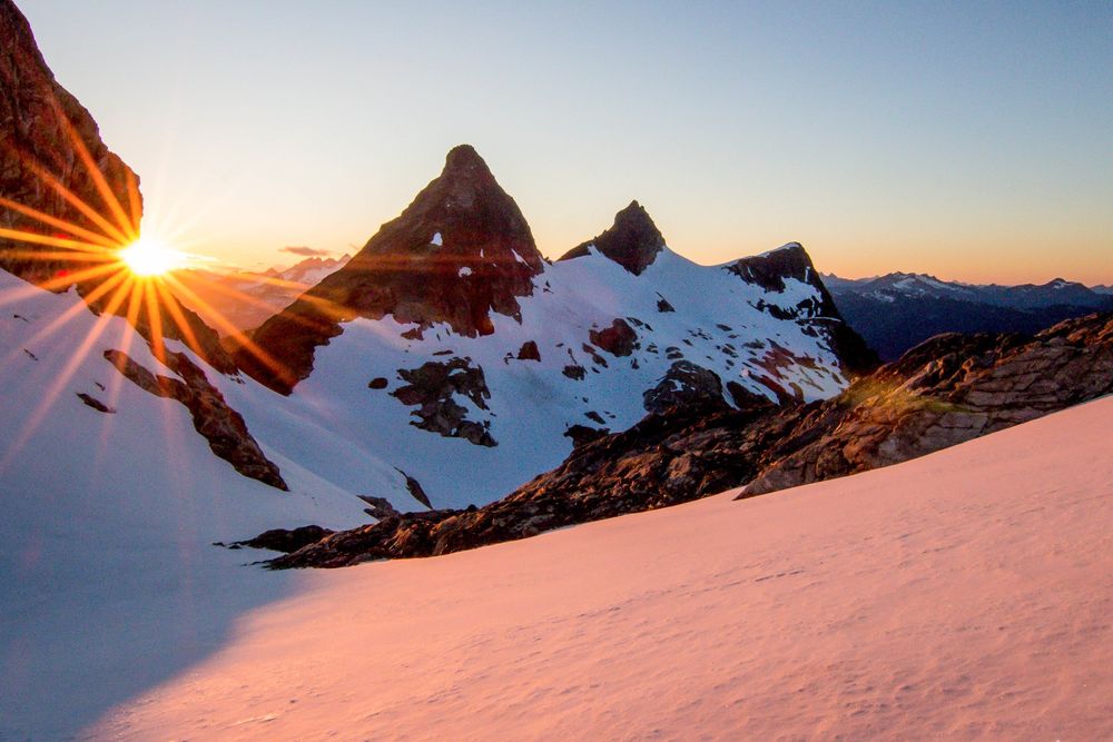Sunset over snowy ridge from Neve Col camp in the North Cascades National Park. Evening Light glows on snow, with Paul Bunyan's Stump, etc. across the Colonial Glacier. 