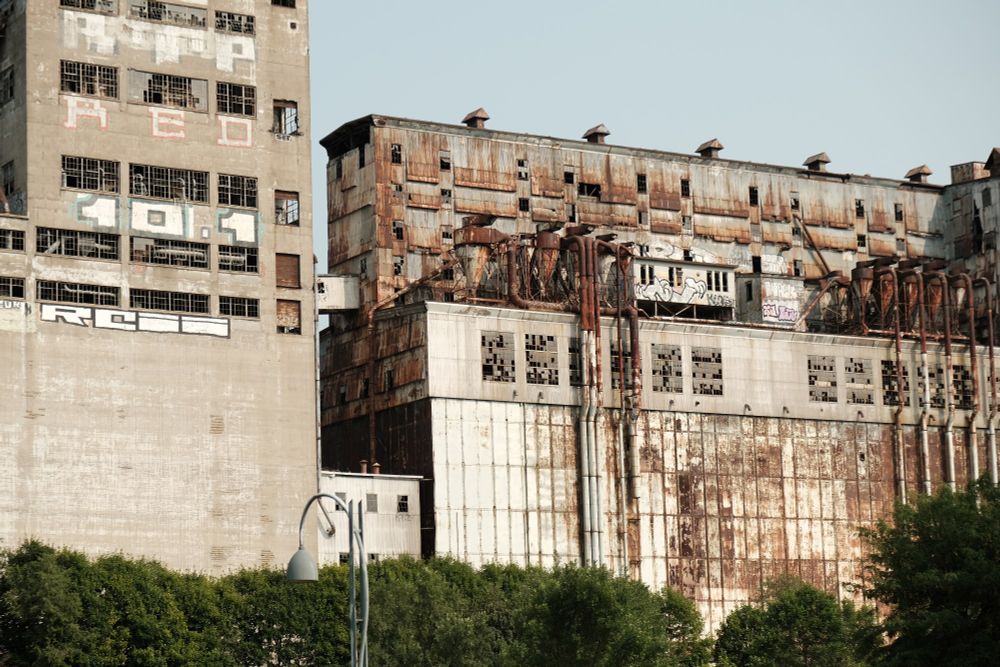 An old abandoned building with broken windows and lots of metal piping on it