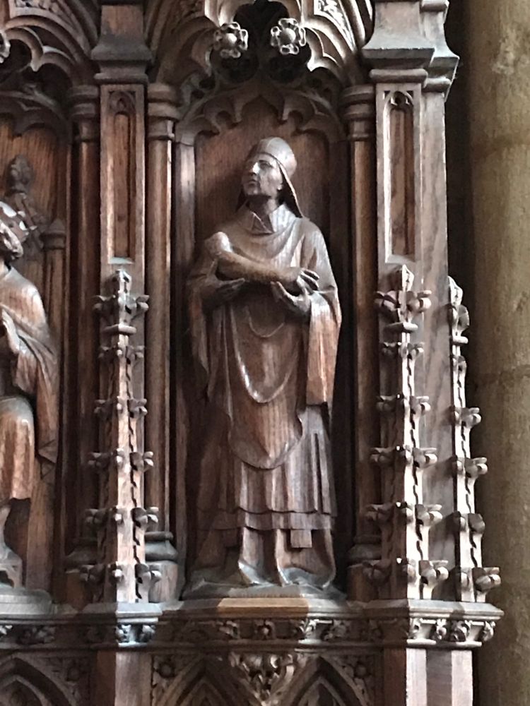 A wooden carving on the stalls in Peterborough Cathedral showing an abbot of Peterborough shown holding Oswald’s arm