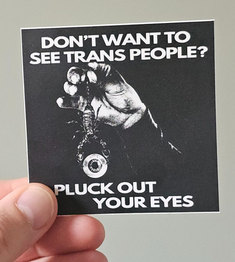 a black and white sticker picturing a hand holding a scorpion by its tail, in its pincers the scorpion holds an eye
text on top and bottom of the image reads "Don't want to see trans people? Pluck out your eyes"