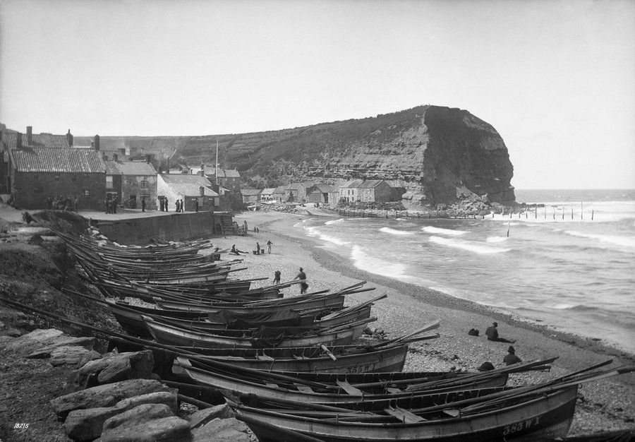 A line of cobles (a type of boat) on the beach at Staithes, looking north west to Cowbar Nab (C.1885). 