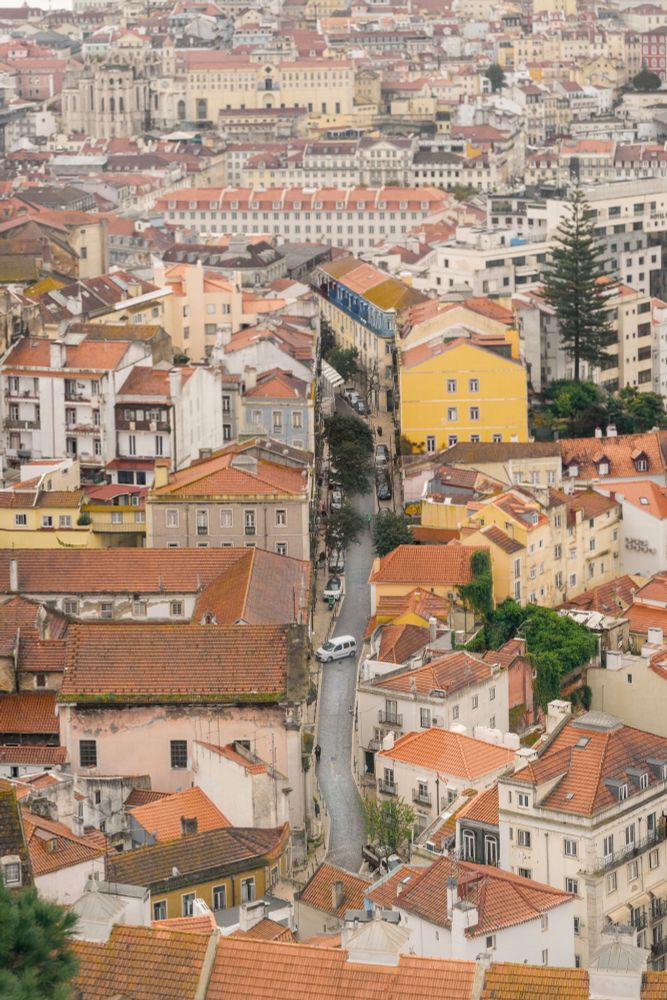 A shot of Lisbon from above. There is focus on a street in the middle of which a car is currently trying to park