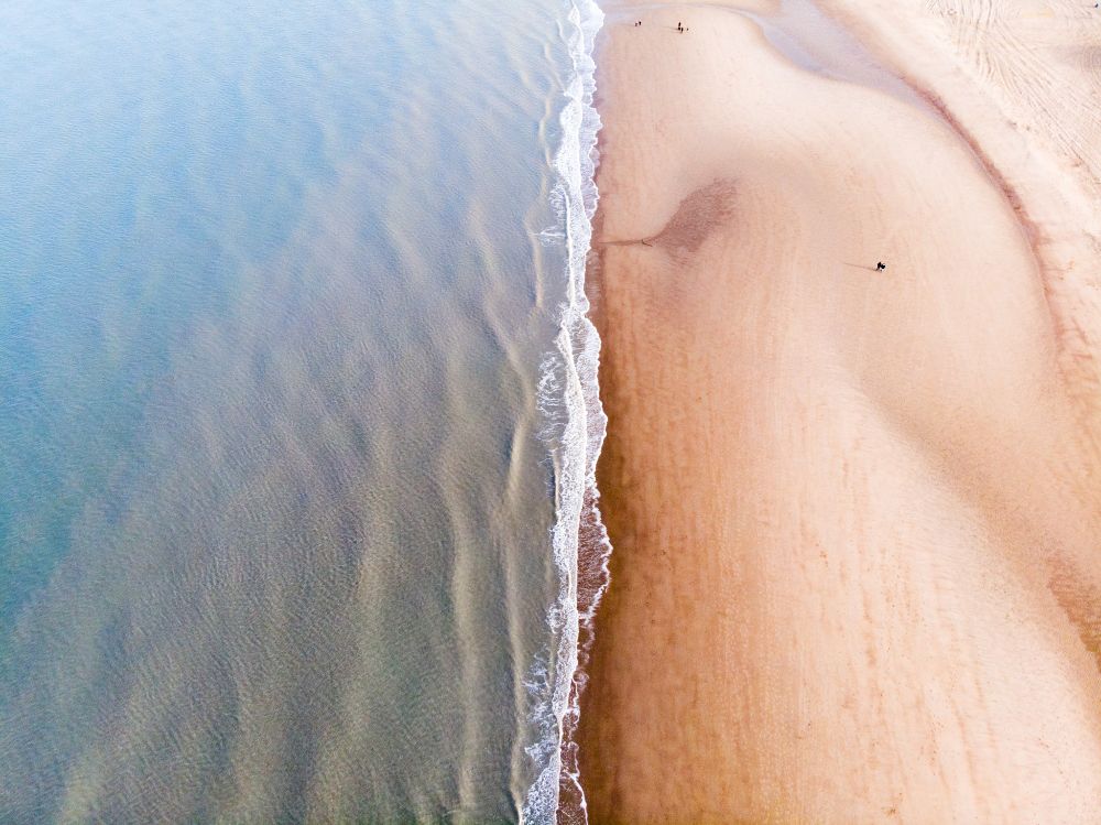 A birds eye view of the ocean shore. A symmetric divide of the sea and land 