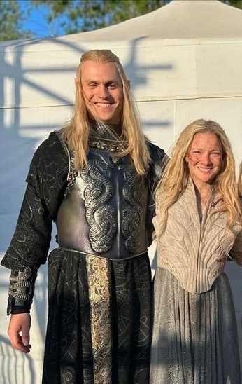 Image of blonde wig Charlie Vickers in his black Sauron outfit from RoP s2 and blonde Morfydd Clark as Galadriel in her silver armour outfit