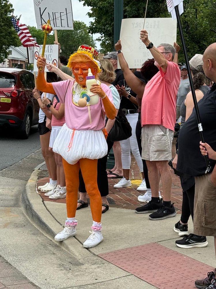 Protestor at #nokings protest dressed like trump waving a scepter and milk bottle