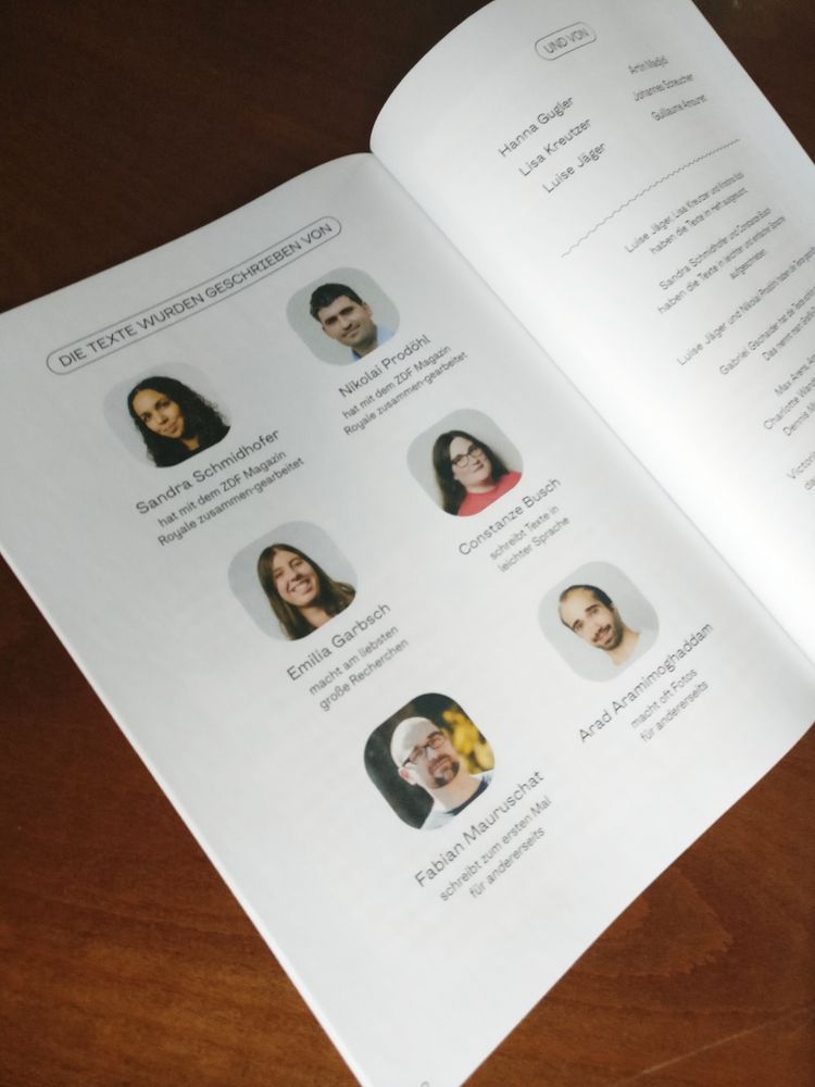 Das Bild zeigt die Doppelseite eines Magazins, das auf einer braunen Holzoberfläche liegt. Auf der linken Seite der Doppelseite ist der Titel "DIE TEXTE WURDEN GESCHRIEBEN VON" zu sehen, gefolgt von einer Reihe von Profilbildern mit den Namen der Autoren und kurzen Beschreibungen ihrer Arbeit. Zu den genannten Personen gehören Sandra Schmidhofer, Nikolai Prodöhl, Constanze Busch, Emilia Garbsch, Fabian Mauruschat und Arad Aramimoghaddam. Auf der rechten Seite der Doppelseite sind die Namen "Hanna Gugler, Lisa Kreutzer, Luise Jäger" über der Überschrift "UND VON" aufgeführt. Darunter folgen weitere Namen und kurze Beschreibungen, die sich auf die Mitarbeit an den Texten beziehen. 