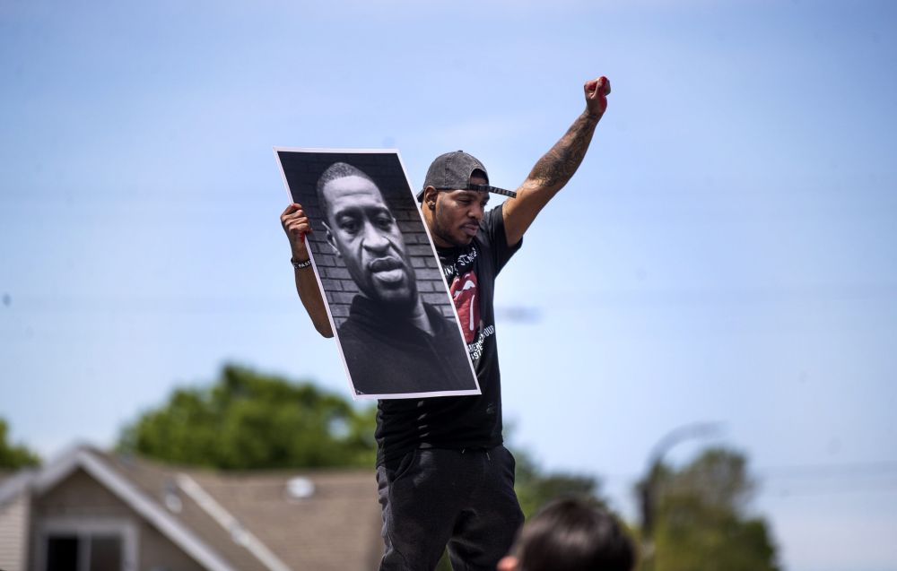 Tony L. Clark holds a photo of George Floyd outside the Cup Food convenience store, near where Floyd was killed, May 28, 2020, in Minneapolis