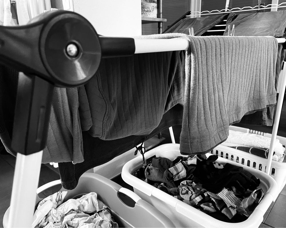 Ein Wäscheständer, unter dem drei Wäschekörbe mit Socken und gewaschenen Handtüchern stehen. Auf dem Ständer hängt Wäsche.