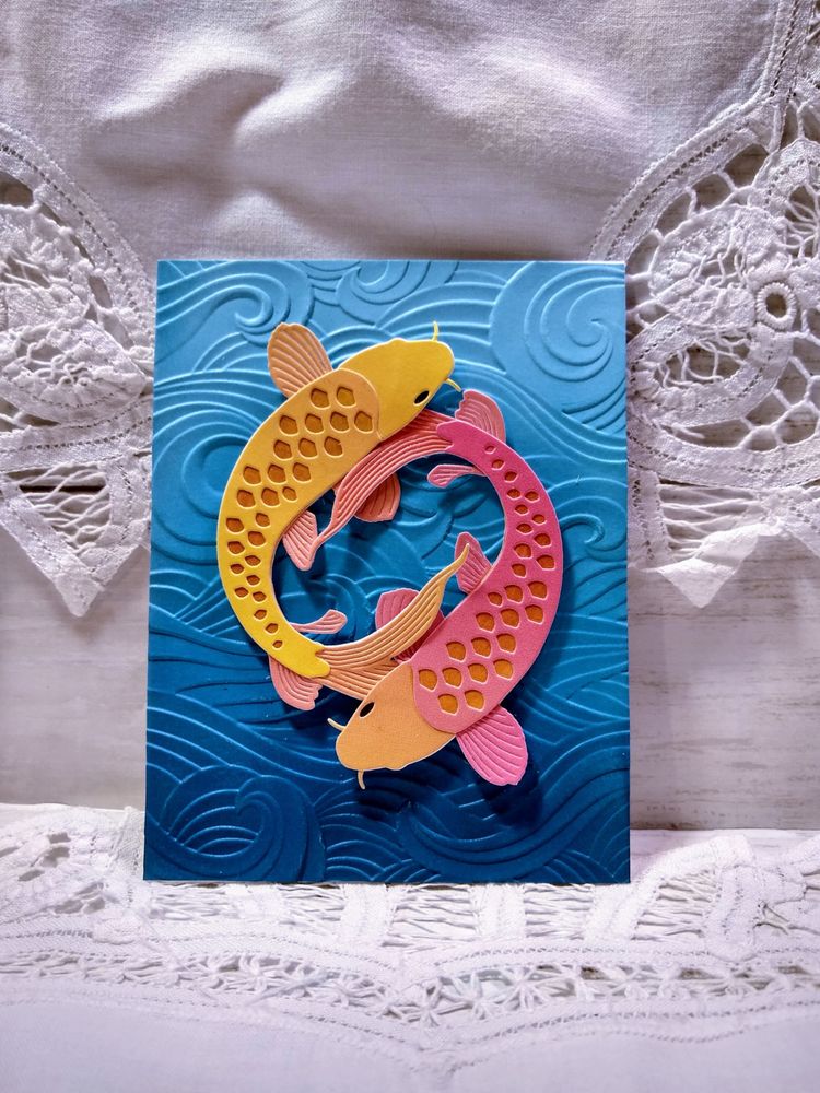 Handmade card showing two layered koi swimming in a circle over dimensional blue ombre waves.
