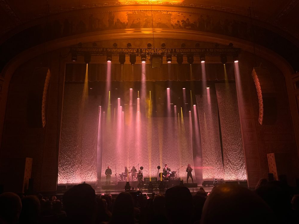 Stage with lots of warm color spotlights pointing both down and up, and members of the band Wardruna