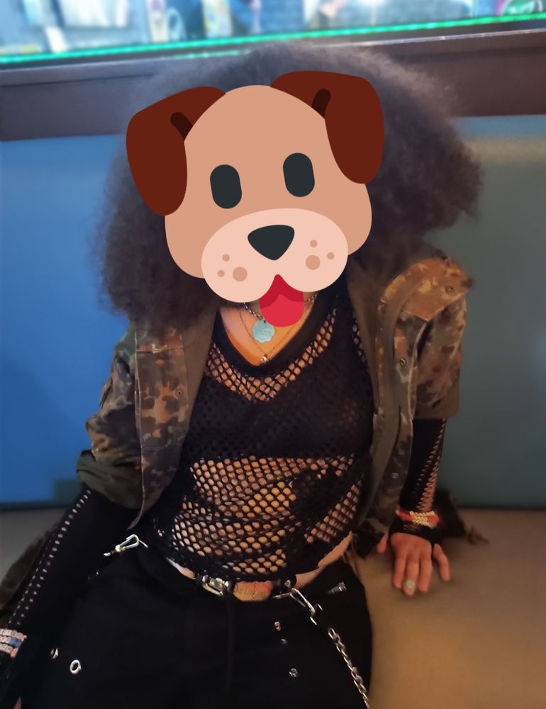 The reference for the sketch. It depicts a young woman in the same outfit minus some minor details like bracelets and gloves) of the poodle sitting on a bench in a bar.