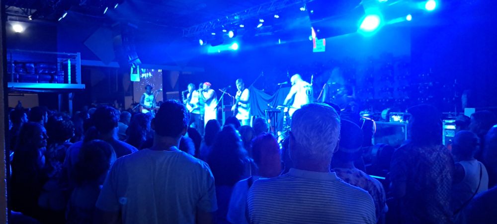 A crowd of people stand in front of a stage watching a band, all bathed in blue light

#snacktime
#phillybands
