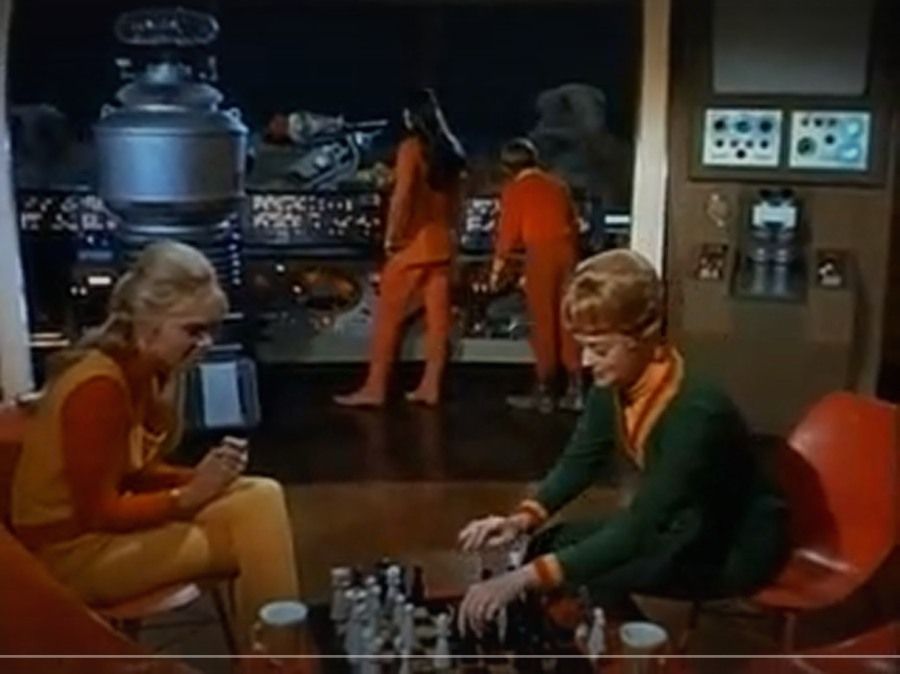 In a 1967 episode of Lost in Space, June Lockhart and Marta Kristen play chess. The family's robot, Angela Cartwright, and Bill Mumy are visible in the background looking out a window.