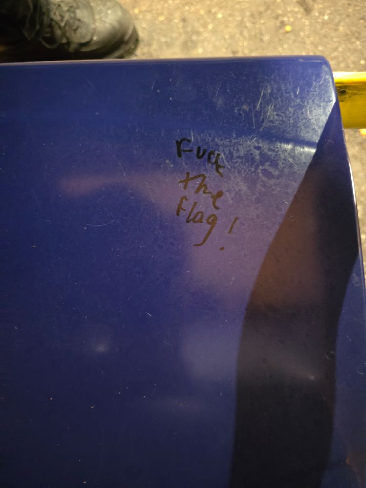 A blue seat with fuck the flag! In black ink