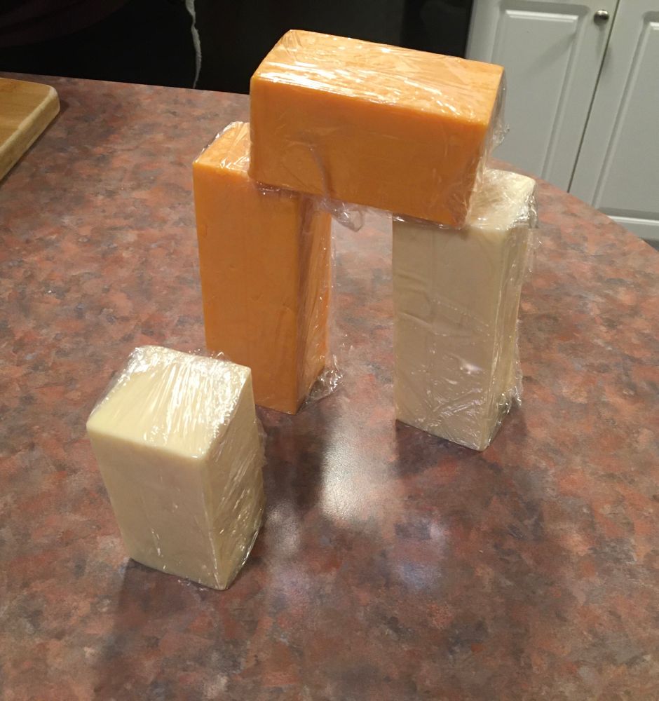A trilithon (a la Stonehenge) made of blocks of cheddar and mozzarella cheese. A smaller standing stone of mozzarella stands in the foreground 