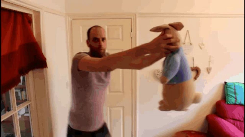 a man holds a stuffed animal in his hands in a living room