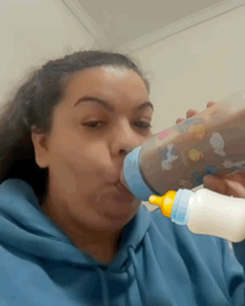 a woman in a blue hoodie drinks from a bottle