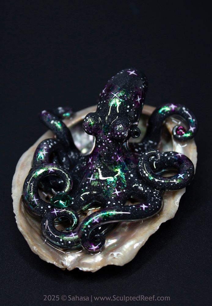 A hand sculpted octopus, lovingly painted in a Nebula theme, sitting in a shell and holding several tiny Swarovski crystals. Photographed on a solid black background.