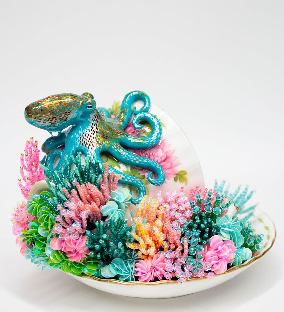 A mixed media artwork featuring a hand sculpted octopus depicting the species Caribbean Reef Octopus. With many colorful hand crafted corals made from tiny glass beads.