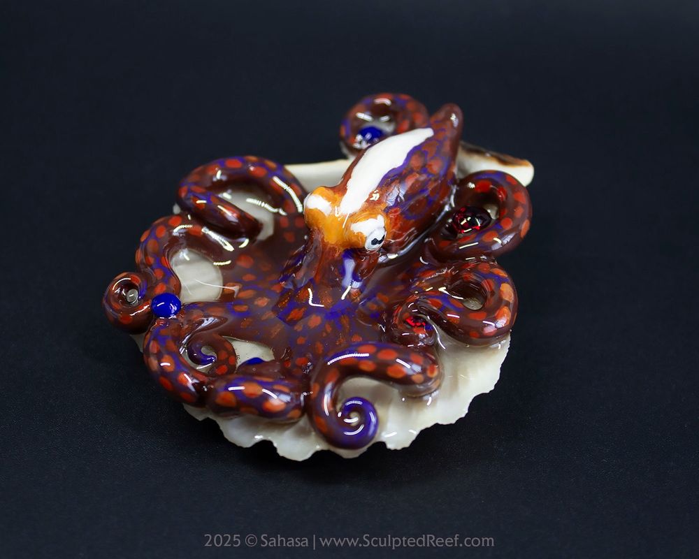 A hand sculpted and painted octopus sculpture, depicting the species Octopus cyanea, also known as the Day Octopus.

This sculpture has a warm brown pattern with subtle patches, a bluish webbed pattern and a big white stripe over the mantle. 

The paintwork represents one of this species most remarkable color expressions.