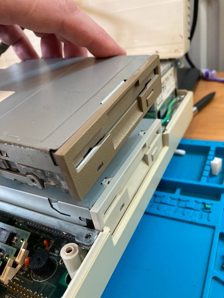 Old floppy drive being held over the new one that I’ve just fitted. 