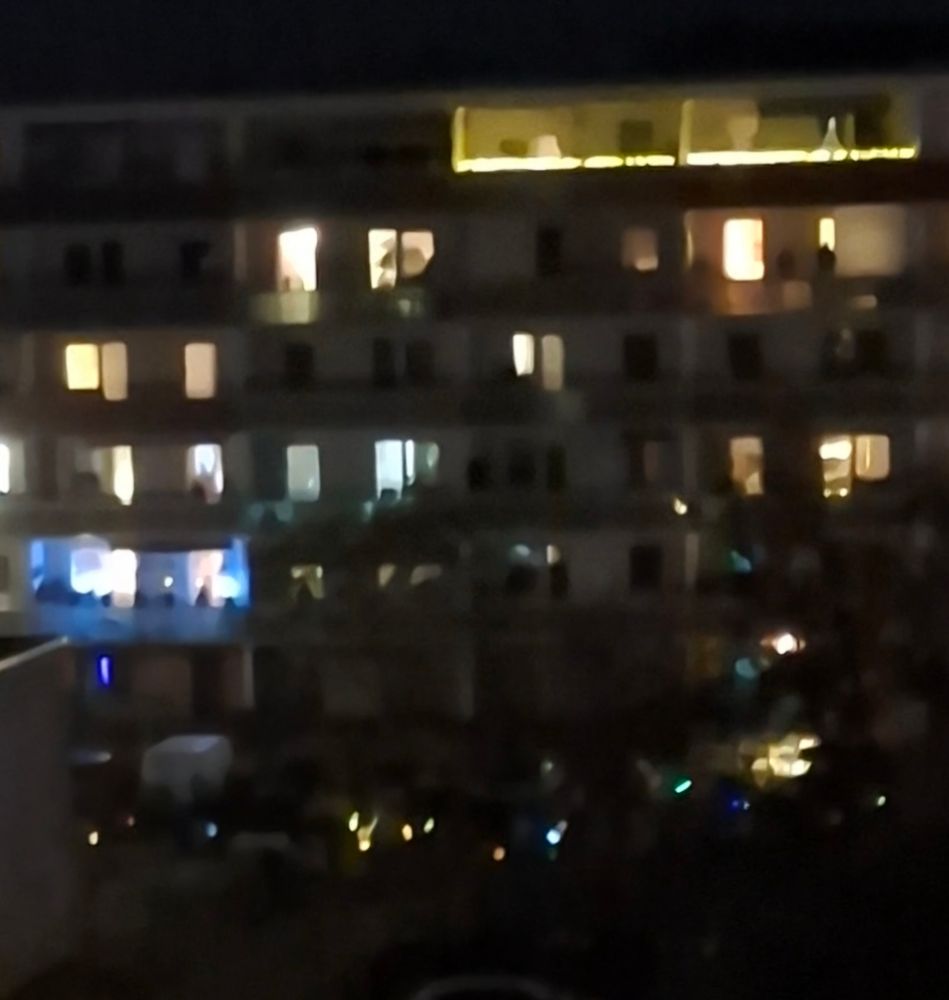 Das Foto zeigt ein beleuchtetes Wohnhaus bei Nacht. In den Fenstern und auf Balkonen brennt Licht, unten sind viele kleine Laternen zu sehen – typisch für den St.-Martins-Tag mit seinen Laternenumzügen.