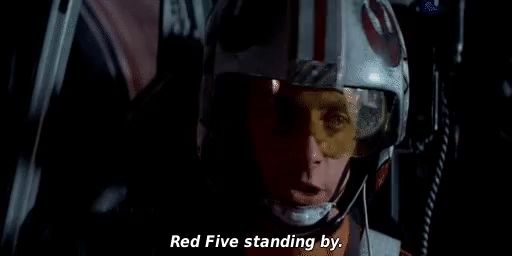 a man wearing a helmet and goggles is standing in a dark room and says `` red five standing by '' .